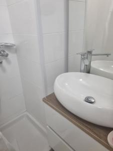 y baño blanco con lavabo y ducha. en Apartman BARBARA, en Vinkovci