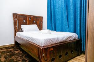 a bed in a room with a blue curtain at MacCinray Villa Kisii in Kisii
