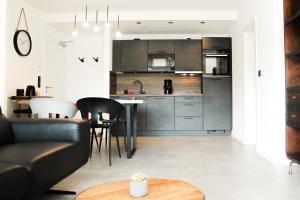 コブレンツにあるMarvel-Apartment - für Freunde & Familien, stadtnah, Parkplatz, E-Ladestation, Gitterbox für Fahrräder, Fitnessstudio, digitale Gästemappe mit Restaurant- und Unternehmenstippsのソファとテーブルのあるキッチンとリビングルーム