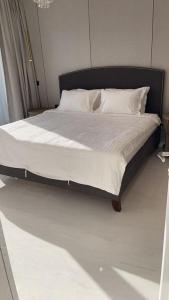 a bed with a black frame and white sheets and pillows at Damac Al Jawharah Tower Apartments in Jeddah