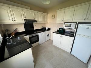 una cocina con armarios blancos y electrodomésticos blancos en Quilty Holiday Cottages - Type B, en Quilty