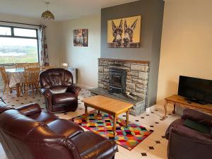 een woonkamer met lederen meubels en een open haard bij Quilty Holiday Cottages - Type B in Quilty