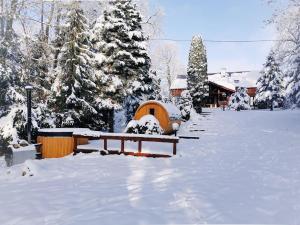 a snow covered yard with a bench and a house at Sielsko i Zacisznie in Ełk