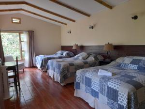 a hotel room with three beds and a window at Estancia del Monje in Cobán