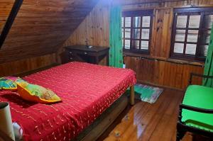 1 dormitorio con 1 cama roja en una habitación de madera en El remanso de Jaure, en Jaureguiberry
