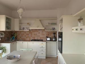 a kitchen with white cabinets and a table in it at Casa Viola vicino al mare by SMART-HOME in Vallecrosia