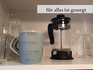 una cafetera sentada en un estante junto a las gafas en Apartment_BaLi, en Linkenheim-Hochstetten