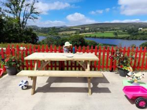 a man sitting at a picnic table in front of a fence at Granny's cottage, a lovely lakeside cottage in Donegal +8 photos