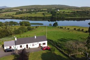 an aerial view of a house in a field with a lake at Granny's cottage, a lovely lakeside cottage in Donegal