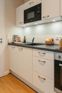 a kitchen with white cabinets and a black counter top at Tien Stuuv in Ratzeburg