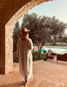 Una mujer caminando a través de un arco hacia una piscina. en Villa à Essaouira, en Essaouira