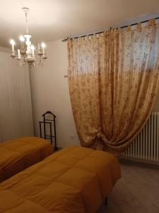 a bedroom with two beds and a curtain at Villa Bersani in CastellʼArquato