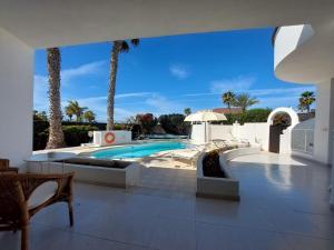 ein Pool in einem Haus mit Palmen in der Unterkunft Sol y Luna Room & Suite Lanzarote Holidays in Playa Blanca