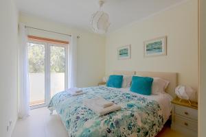 a bedroom with a bed with blue pillows and a window at Penthouse Cassia in Cabanas de Tavira +10 photos