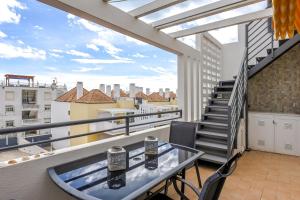 a balcony with a glass table and a staircase at Penthouse Cassia in Cabanas de Tavira
