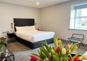 a bedroom with a bed and flowers in a room at Bella Vista Hotel & Self Catering Suites in Cobh