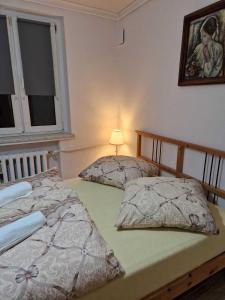 two beds in a bedroom with a lamp on the wall at Apartament w Centrum in Prudnik