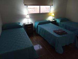Habitación de hotel con 2 camas y 2 lámparas en Deptos La Punta en La Punta