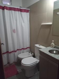 y baño con aseo y cortina de ducha. en Deptos La Punta en La Punta