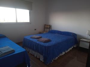 1 dormitorio con 2 camas con sábanas azules y ventana en Deptos La Punta en La Punta