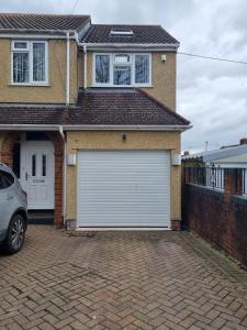 une porte de garage blanche sur le côté de la maison dans l'établissement Large Kingsize ensuite in Kingswood, Bristol, BS15, à Kingswood