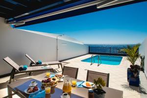 a balcony with a table with food and a pool at FRONTLINE VILLA 26, Modern Coastal Design with Amazing Views in Puerto Calero