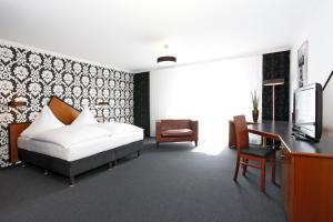 a bedroom with a bed and a desk and a television at Hotel Apartment Laforsch in Dreieich