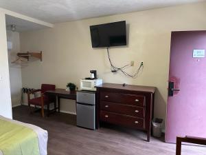 a room with a bed and a desk and a tv on the wall at Heritage Inn in Uniontown