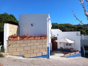een wit huis met een patio en een parasol bij CASA ISABEL - (ZONA RURAL) in Fasnia
