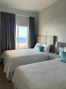 two beds in a bedroom with a view of the ocean at Tramonto Boutique Hotel in La Ceiba