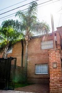 dos palmeras frente a un edificio de ladrillo en Alojamiento La Palmera en Saladillo