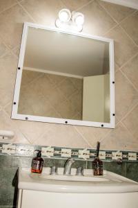 lavabo en el baño con un espejo grande encima. en Alojamiento La Palmera en Saladillo