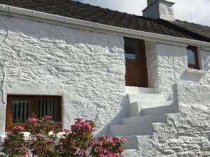 a white brick house with stairs and flowers at Little Barn Cottage in Newport Pembrokeshire