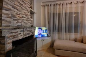 sala de estar con TV y chimenea de piedra en Seaview Country House, en Sarandë