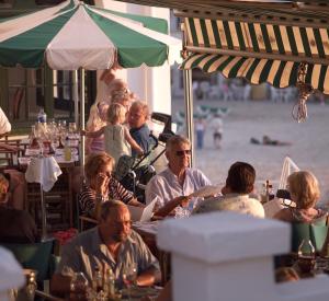 grupa ludzi siedzących przy stołach przy plaży w obiekcie Hotel Bahia w mieście Cala Santandria