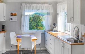 a kitchen with white cabinets and a table and a window at Nice Home In Leknes With House Sea View in Leknes