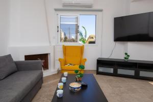 een woonkamer met een bank en een gele stoel bij Villa suncity Boutique Beachfront in Ayia Napa