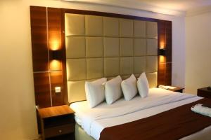 a bedroom with a large bed with a large headboard at Presken K-ONE in Ikeja