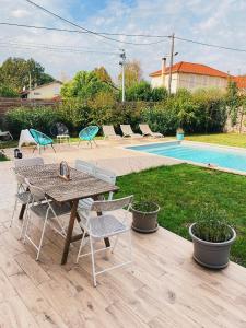 a table and chairs on a patio with a pool at Maison chaleureuse in Villeneuve-sur-Lot
