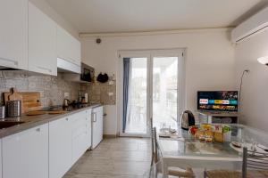 cocina con armarios blancos y ventana grande en Il Gattino di Porto - apt 2 - Bilocale terrazzo piscina, en Imperia