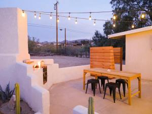 a wooden table and chairs on a patio with lights at The Zen - Outdoor Shower, Gas Fireplace, Walkable to Shops & Restaurants in Joshua Tree