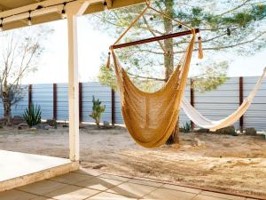 a hammock hanging from a pole in a yard at The Zen - Outdoor Shower, Gas Fireplace, Walkable to Shops & Restaurants in Joshua Tree