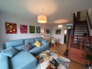 Nuevo apartamento de dos plantas في Renedo de Piélagos: غرفة معيشة مع أريكة زرقاء ودرج