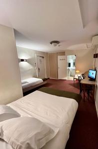 a hotel room with a bed and a desk with a computer at Logis Hôtel Teyssier in Uzerche