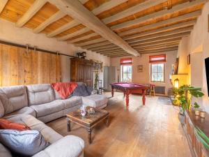 een woonkamer met een bank en een pooltafel bij Magnificent square farm in the beautiful blossom region in Sint-Truiden