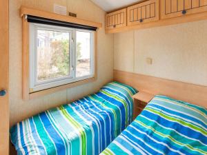two beds in a small room with a window at Mobile Home in Var near Miramar Beach in La Londe-les-Maures +27 photos