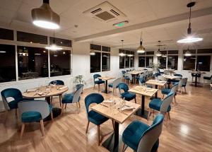 un restaurant avec des tables en bois et des chaises bleues dans l'établissement Logis Hôtel Teyssier, à Uzerche