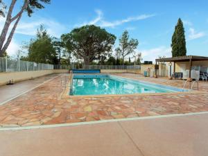 a swimming pool with a stone patio and a fence at Mobile Home in Var near Miramar Beach in La Londe-les-Maures