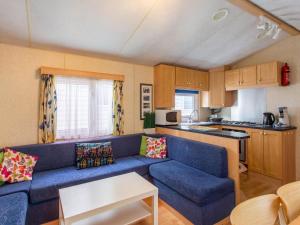 Mobile Home in La Londe-les-Maures with Terrace في لا لوند-ليه-مور: غرفة معيشة مع أريكة زرقاء ومطبخ