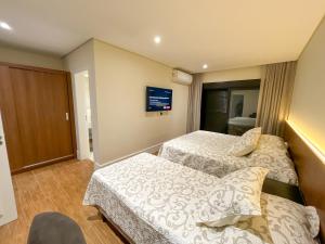 a hotel room with two beds and a tv at Pousadinha Campos in Campos do Jordão